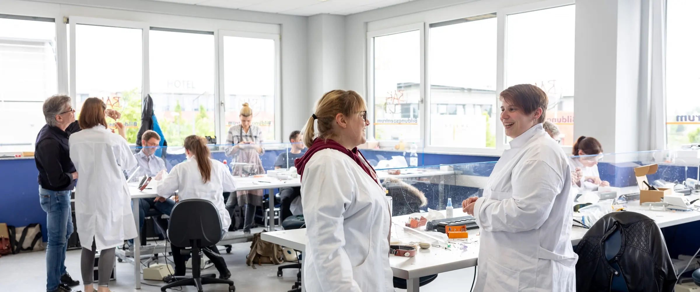 Teilnehmende arbeiten an den Werkbänken der Augenoptik-Werkstatt am Campus